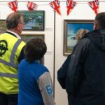 Volunteer Mike French and others take time out to enjoy the Mark Bromley paintings